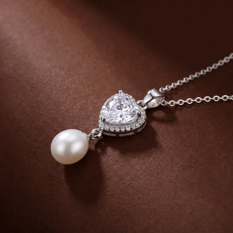 Close-up of the clear heart and pearl pendant on cocoa