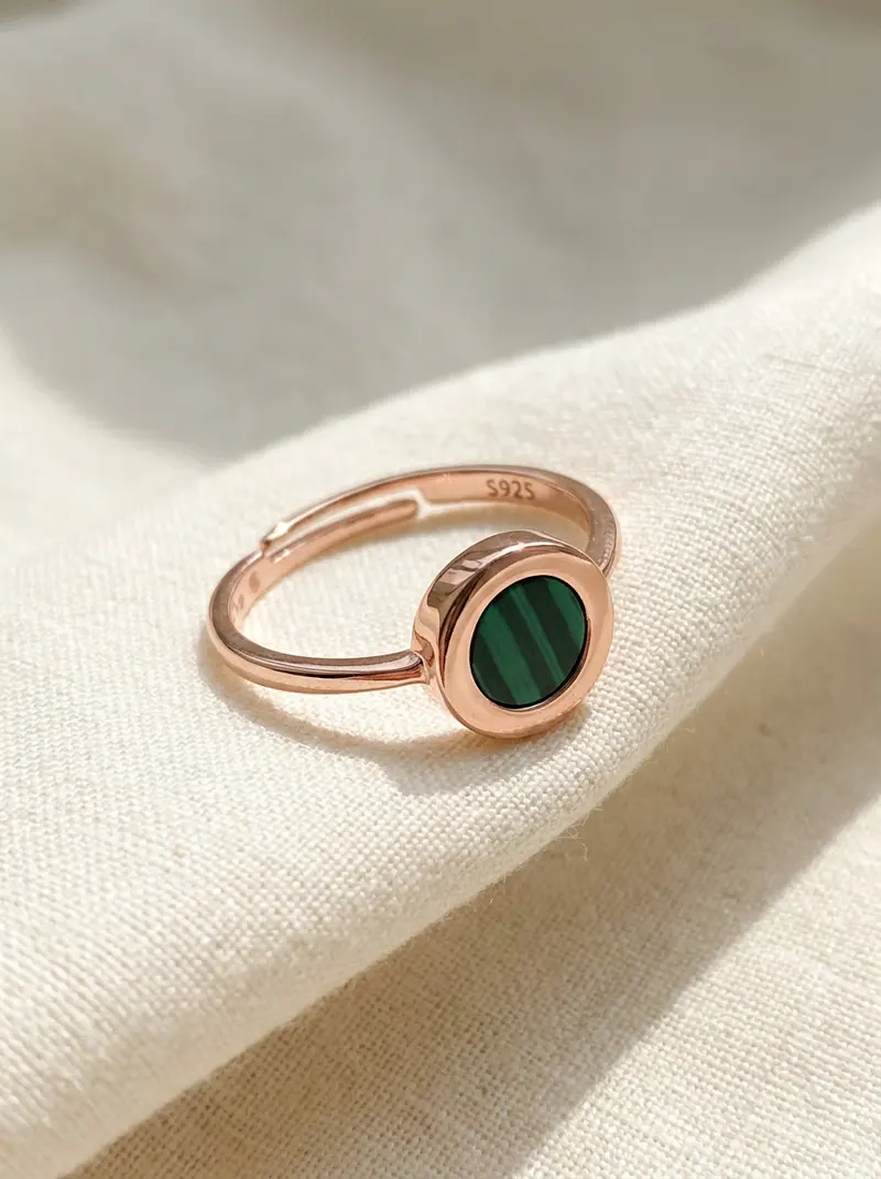 Close-up of the rose-gold malachite round ring on folded linen