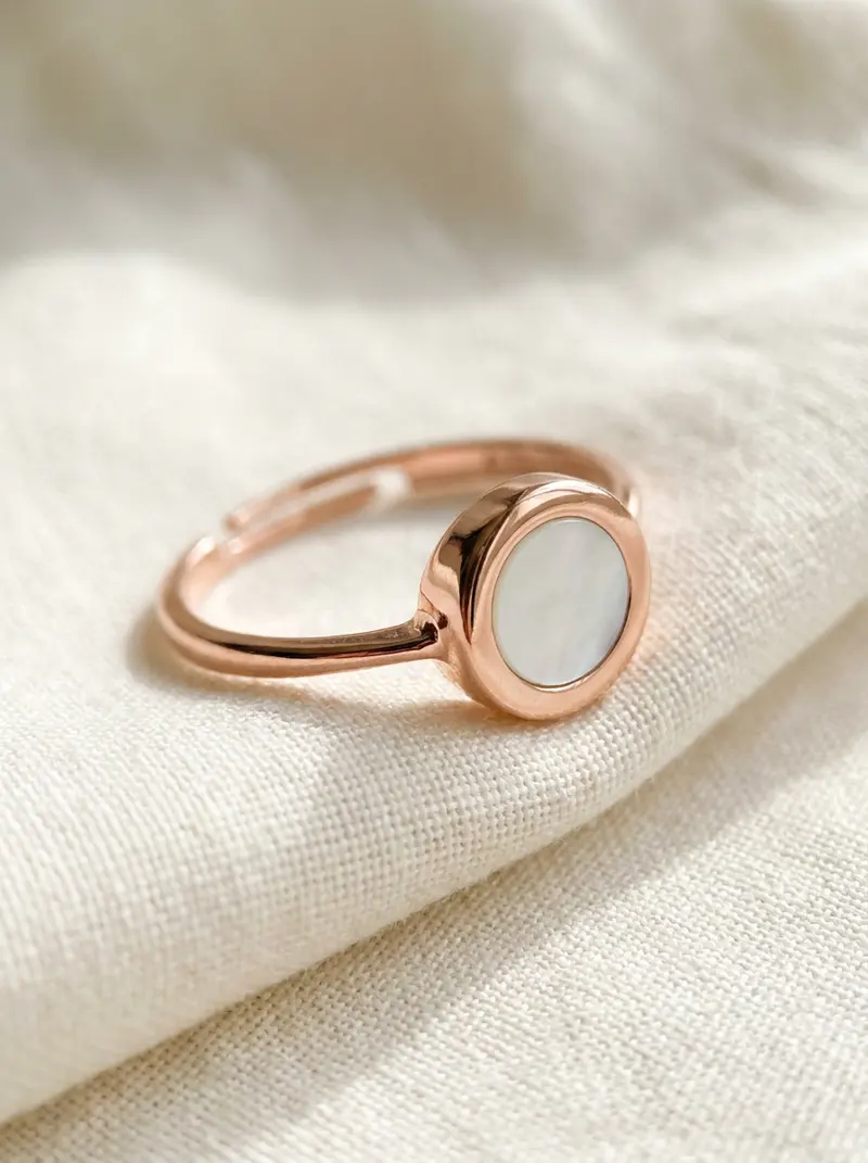 Close-up of the rose-gold mother-of-pearl round ring on folded linen