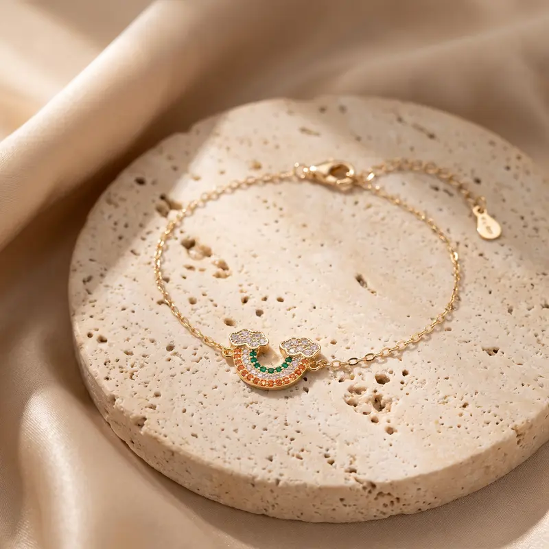 Gold-finish rainbow cloud bracelet on a travertine disc