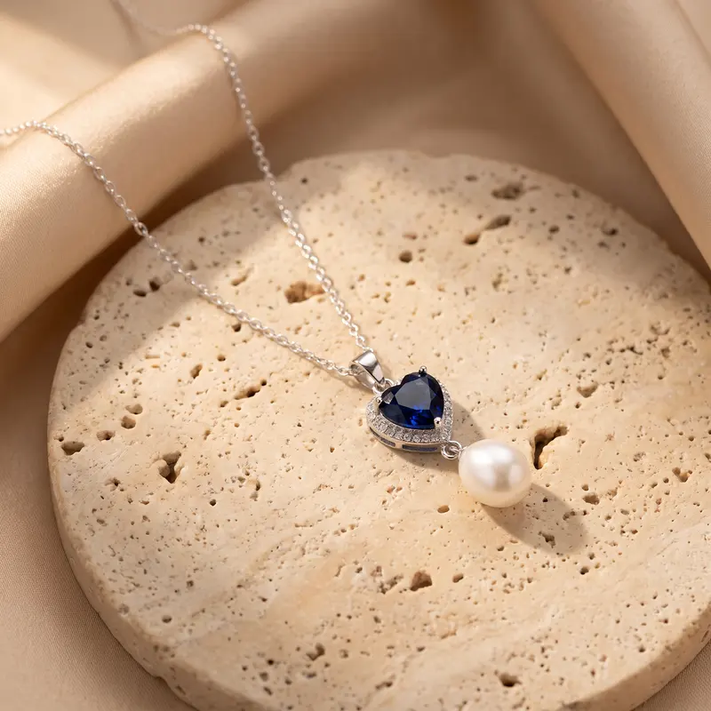 Sapphire-blue heart and pearl pendant on a travertine disc
